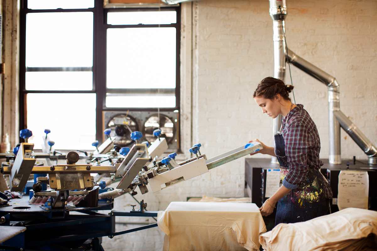 Female worker printing on t-shirt in workshop